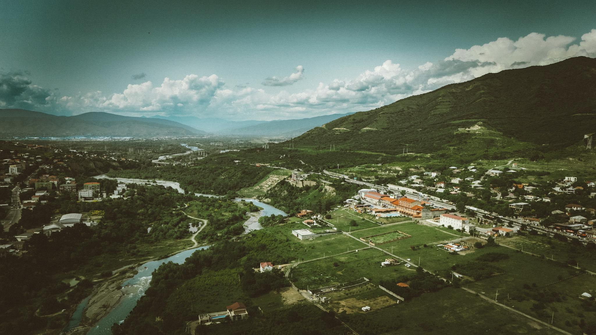 Scenic aerial shot of a verdant valley and river in Georgia, showcasing natural beauty.